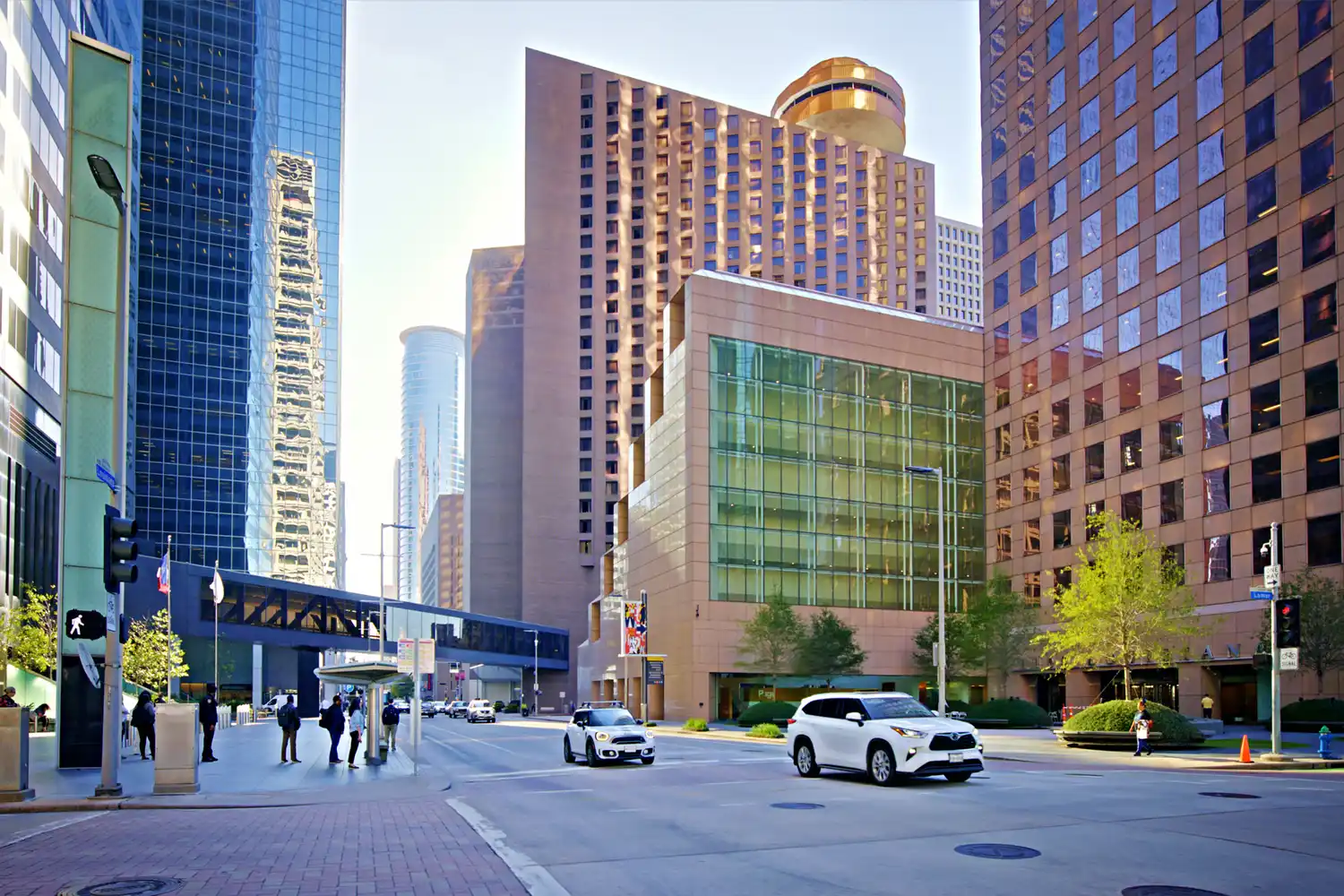 A street-level view of downtown Houston's skyscrapers and pedestrian crosswalks.