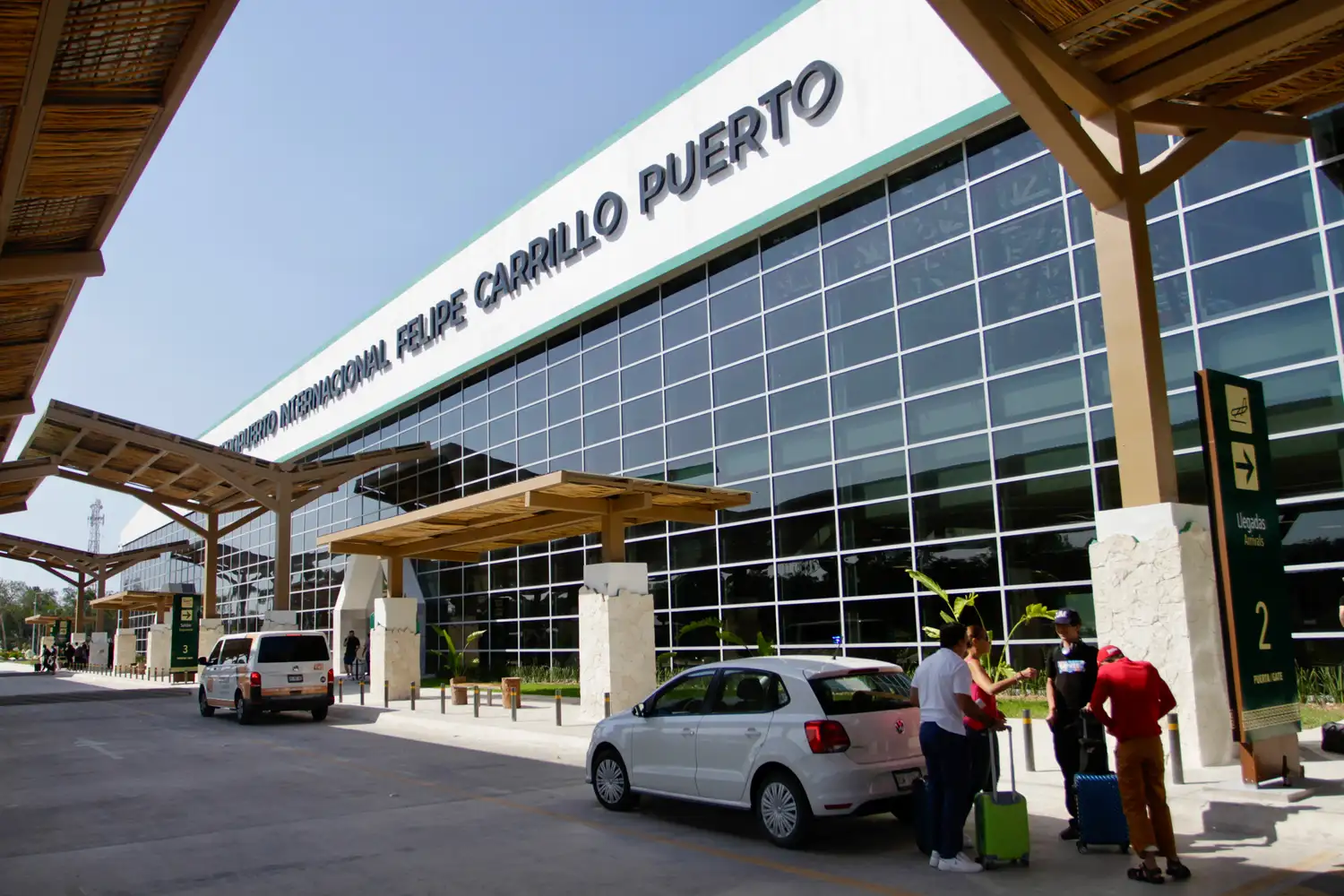 The exterior of the Felipe Carrillo Puerto International Airport in Tulum with travelers and taxis.