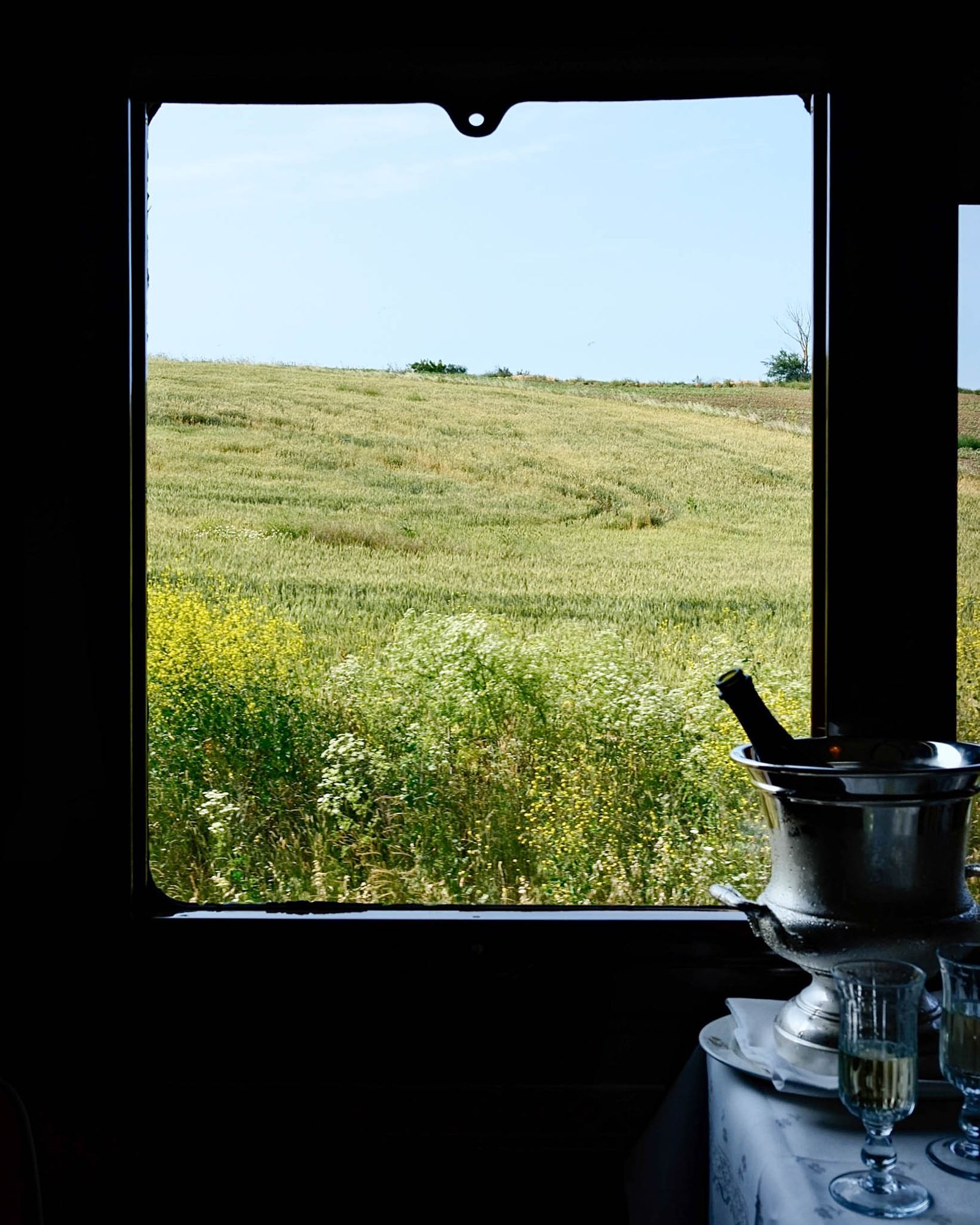 A view of the passing European landscape seen through a vintage train window frame.