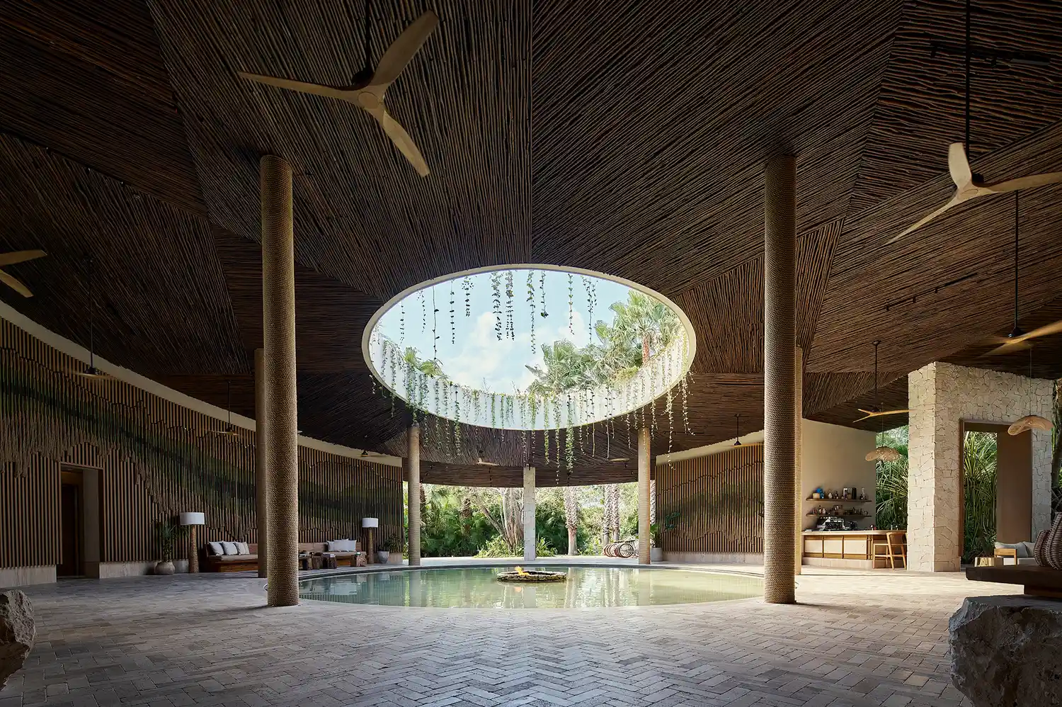 Lobby area at Alila Mayakoba with an open ceiling design and central water feature.