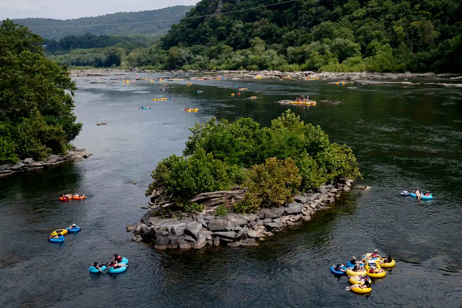 People tubing down the Potomac River with hills in the background.
