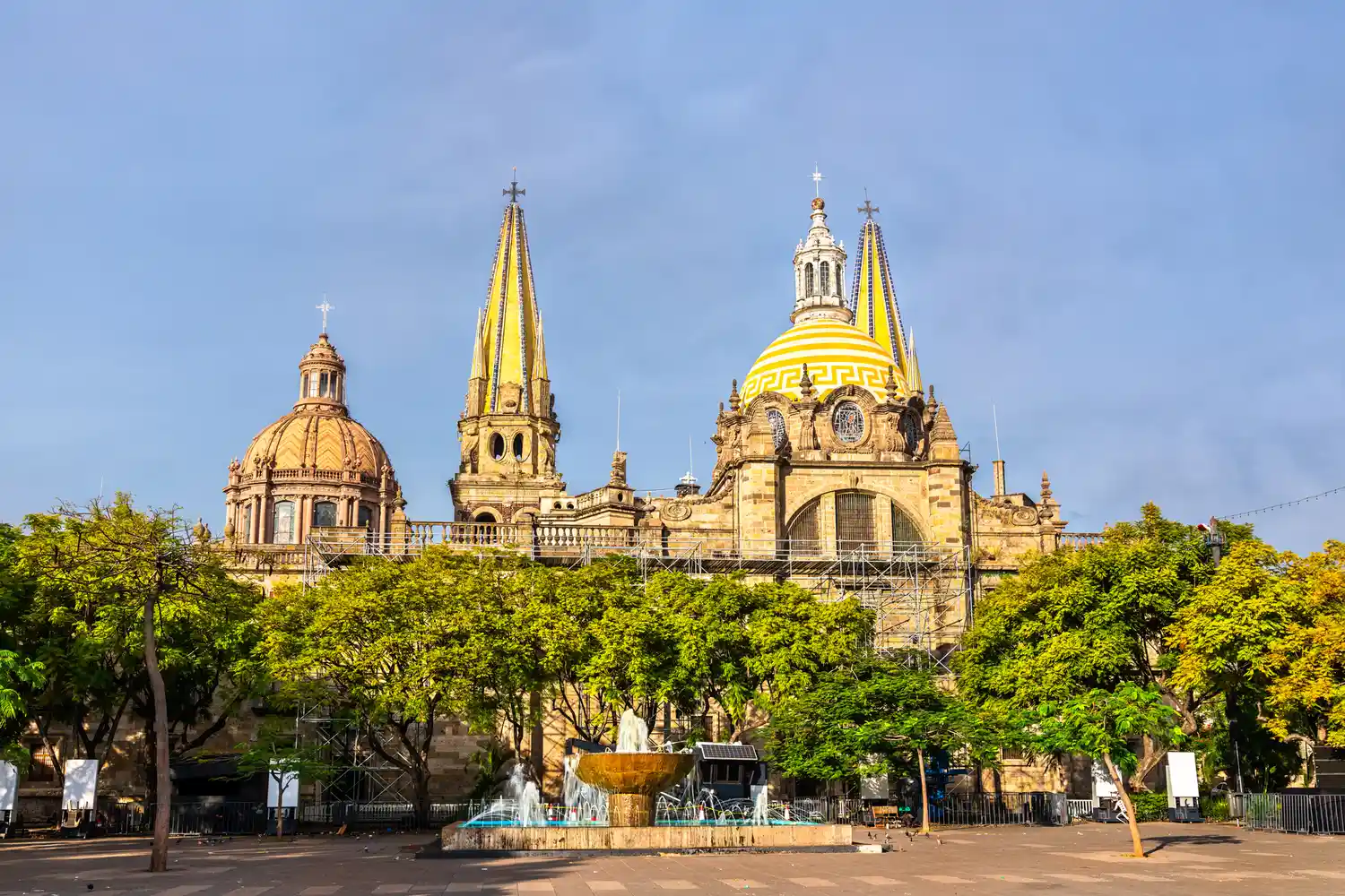 Exterior view of the ornate Cathedral of the Assumption of Our Lady in a sunlit plaza in Guadalajara.