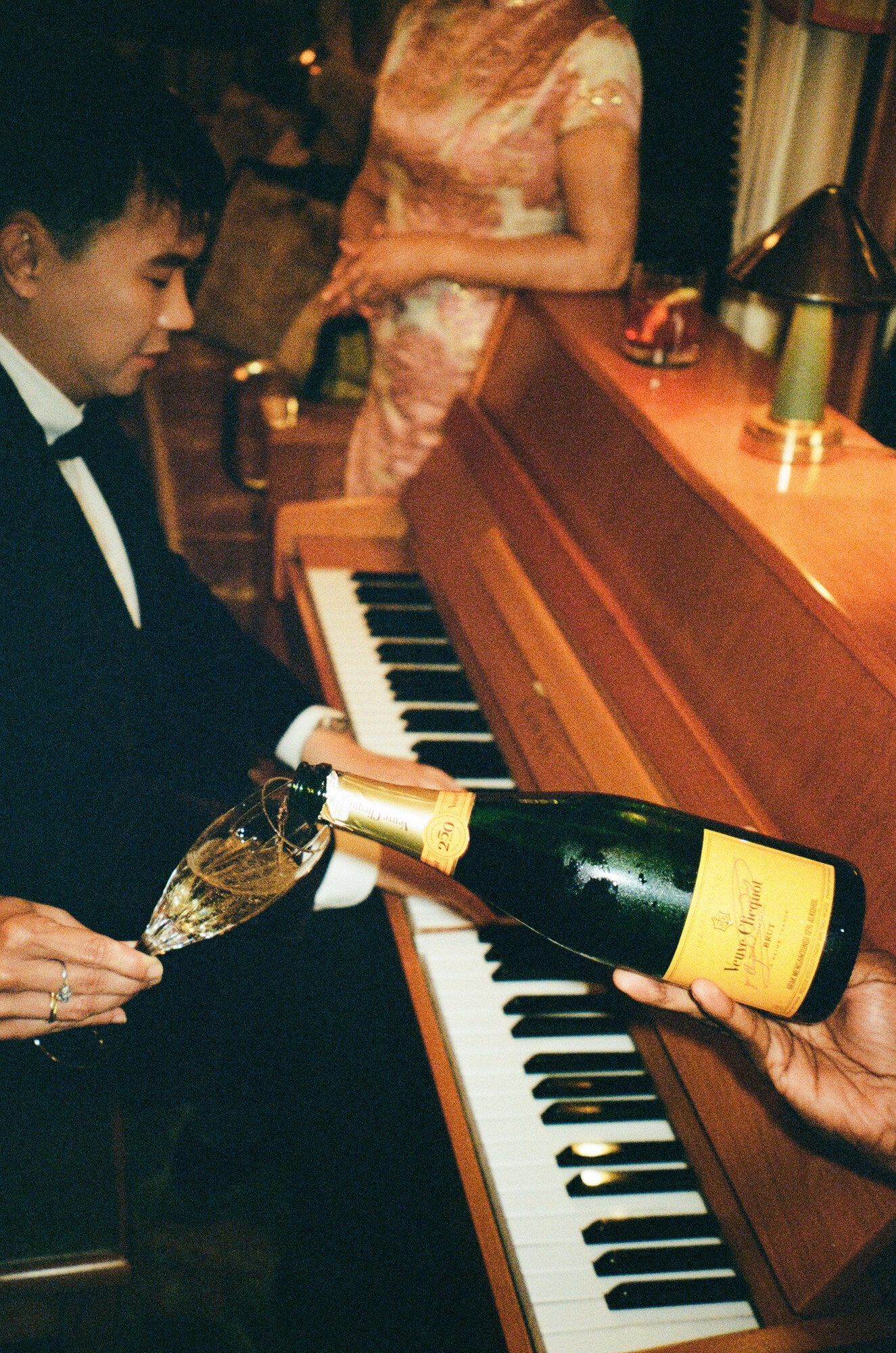 A pianist playing a grand piano in a dimly lit, luxurious lounge car.