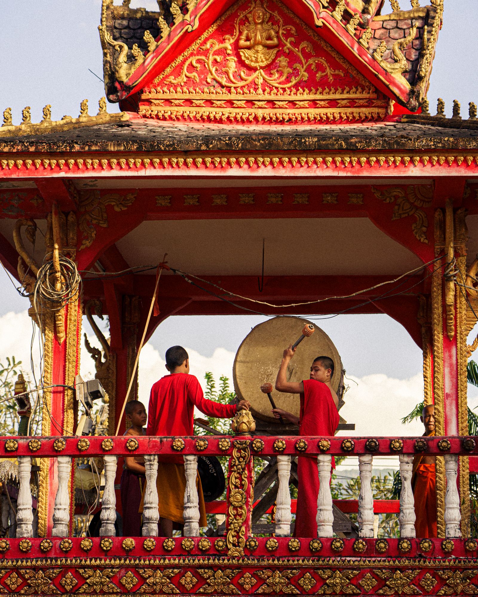 Buddhist monks walking past traditional Laotian temple architecture.