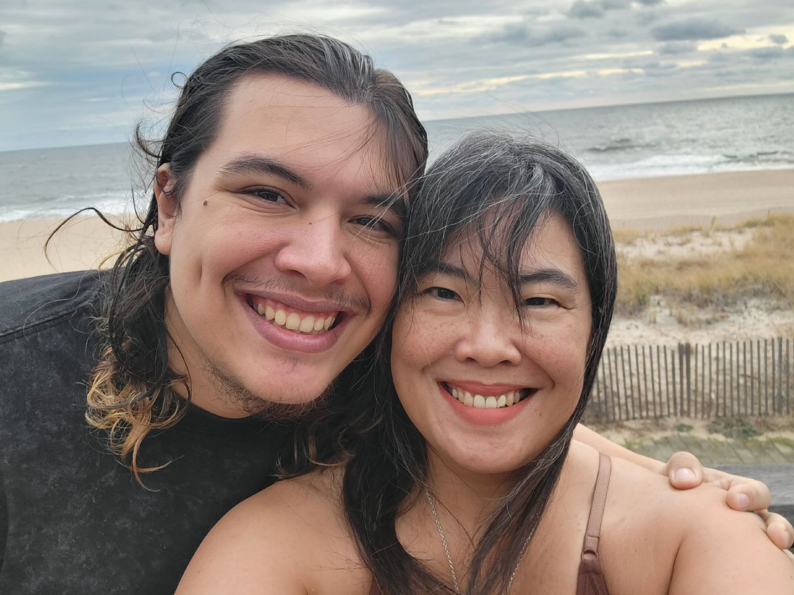 A happy mother and adult son smiling together during a beach-side wellness activity.
