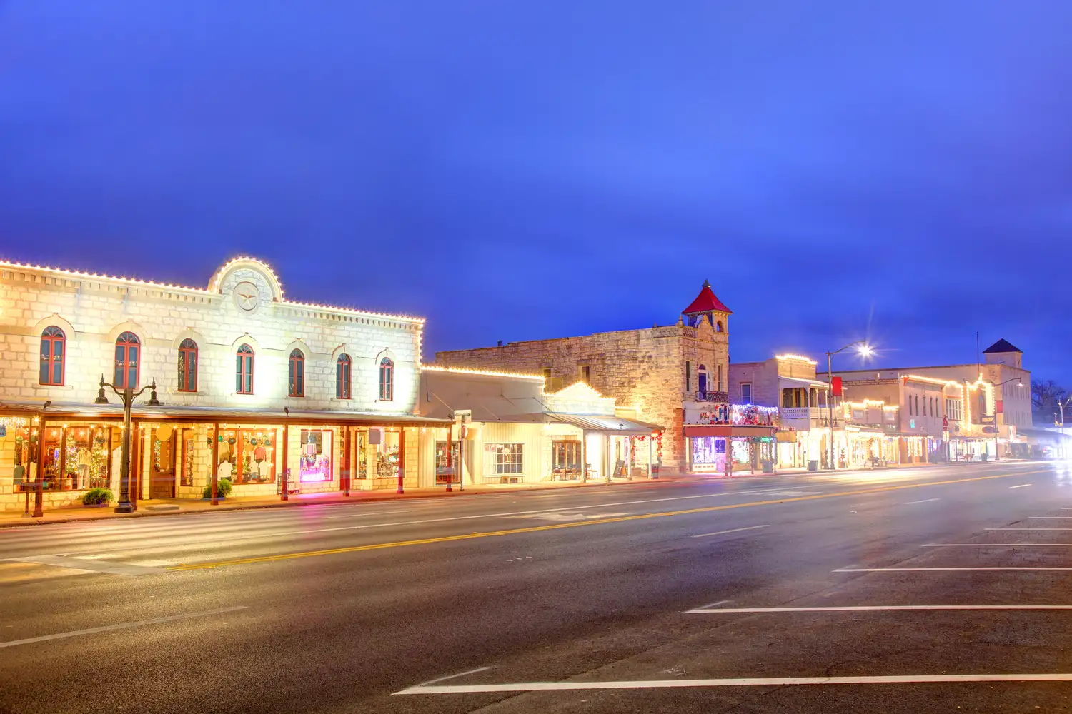 A long exposure night shot of Fredericksburg's lit-up historic buildings and streetlights.