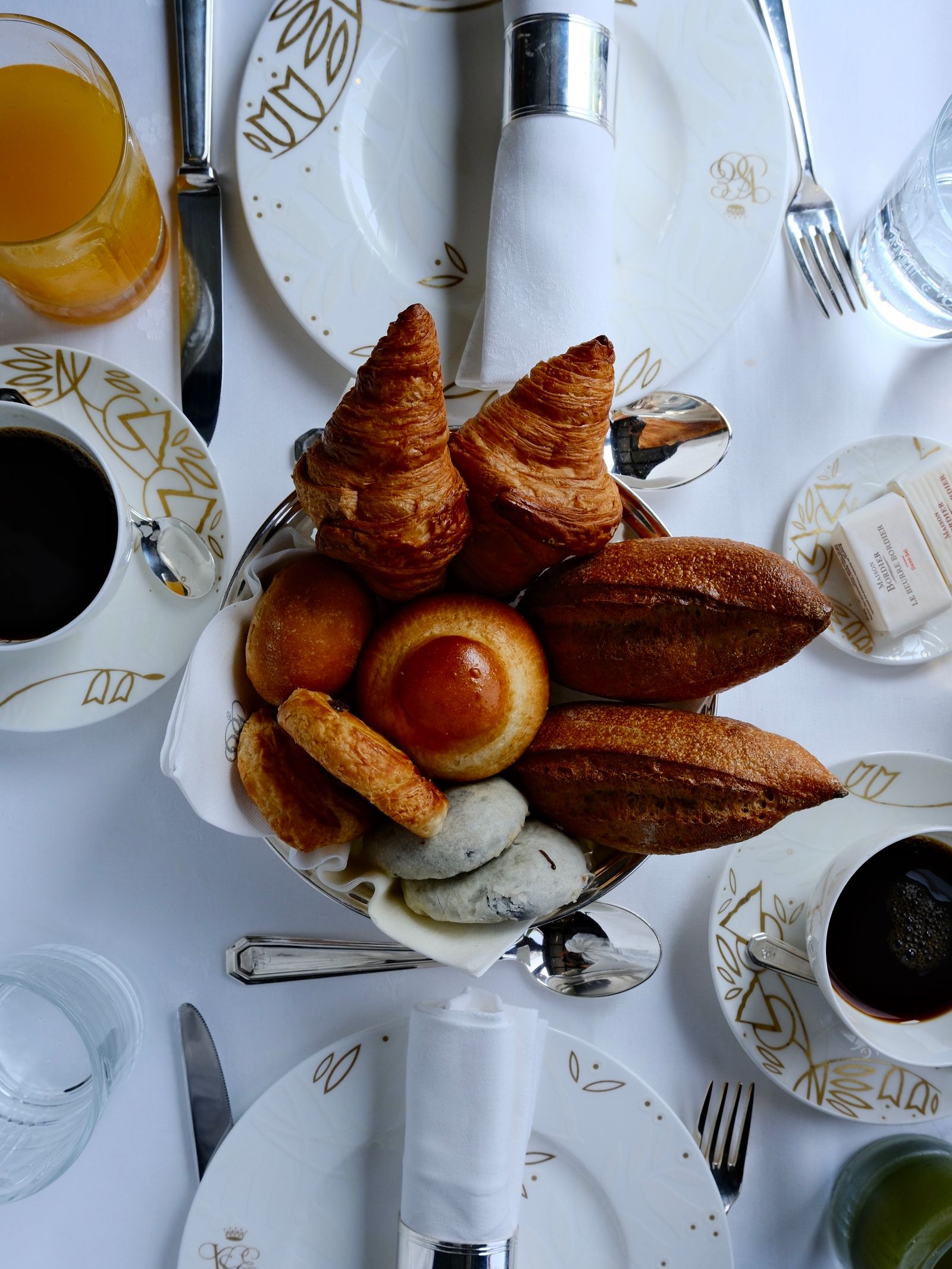 A close-up of a gourmet brunch spread including fresh bread and fine cutlery on the train.