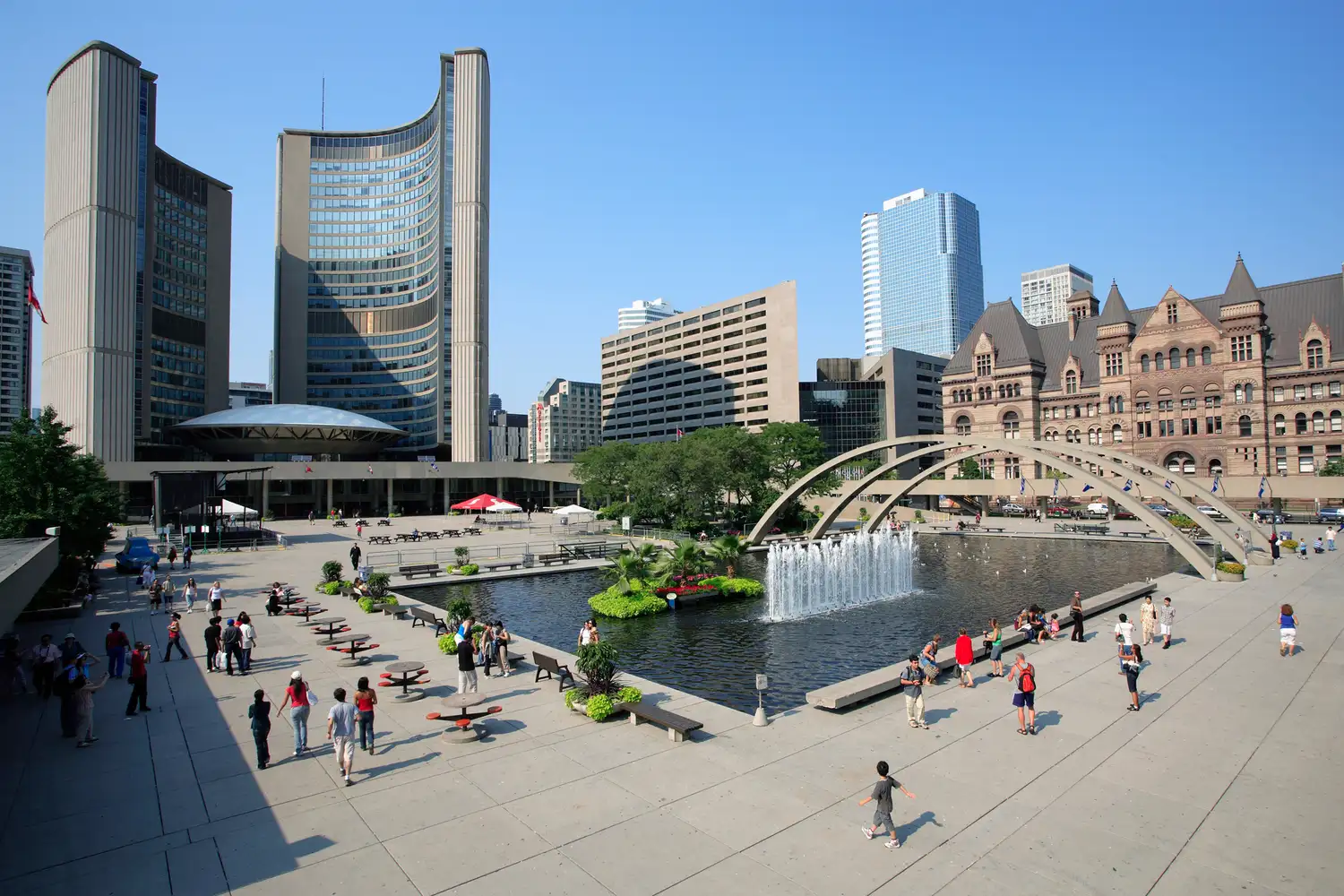 A lively crowd at Nathan Phillips Square in Toronto with the City Hall arches and reflecting pool.