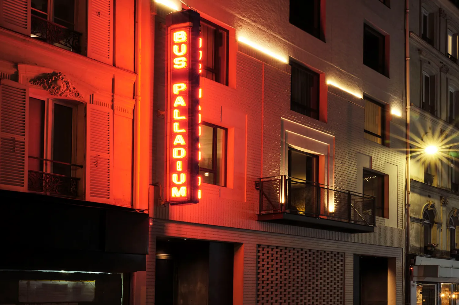 The illuminated Bus Palladium neon sign on the exterior of the building at night.