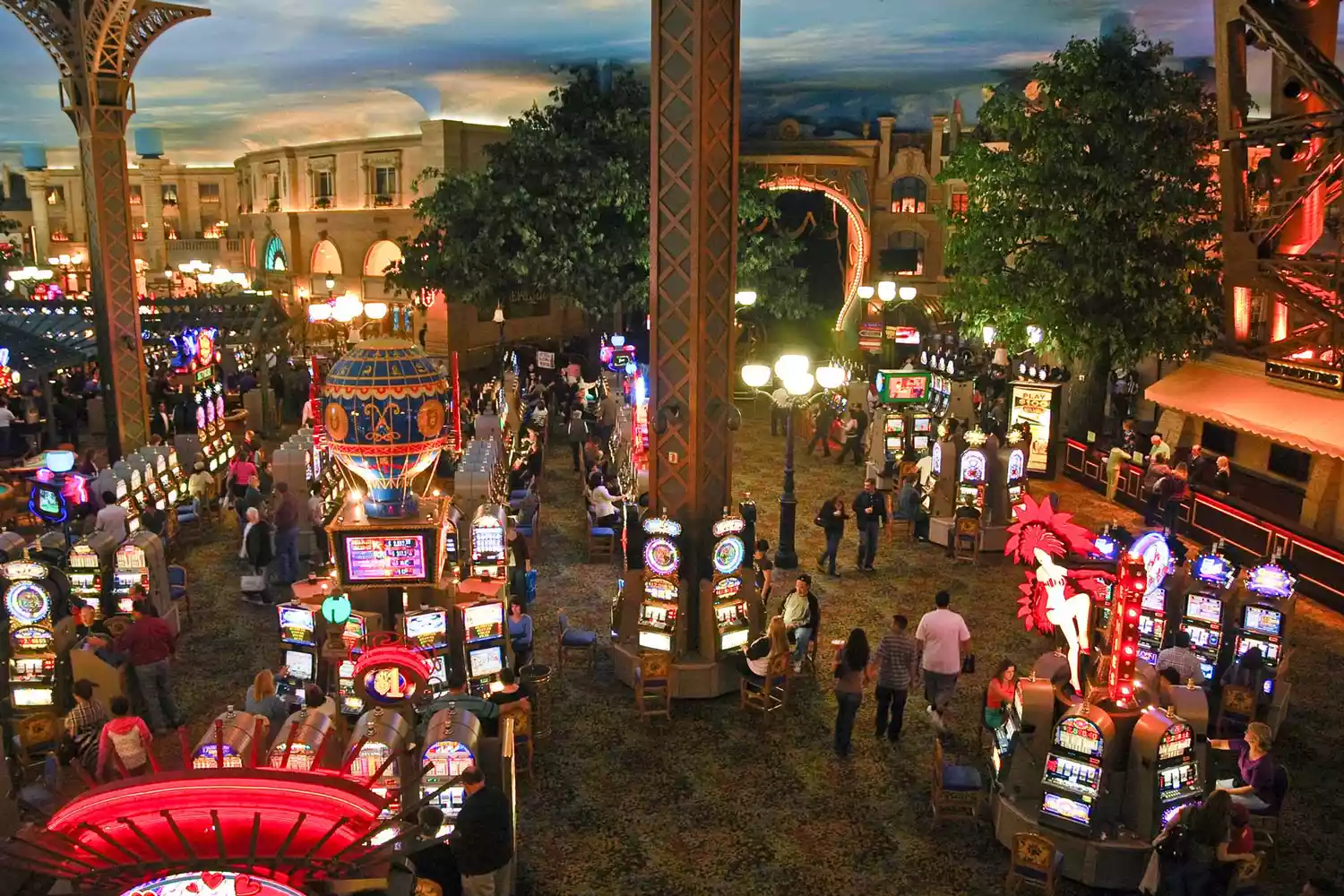 Wide view of a busy casino floor with numerous people and gaming tables.