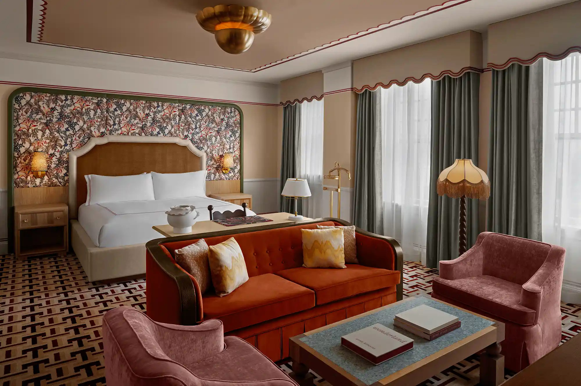 A luxury hotel suite featuring patterned wallpaper, upholstered furniture, and a spacious layout.