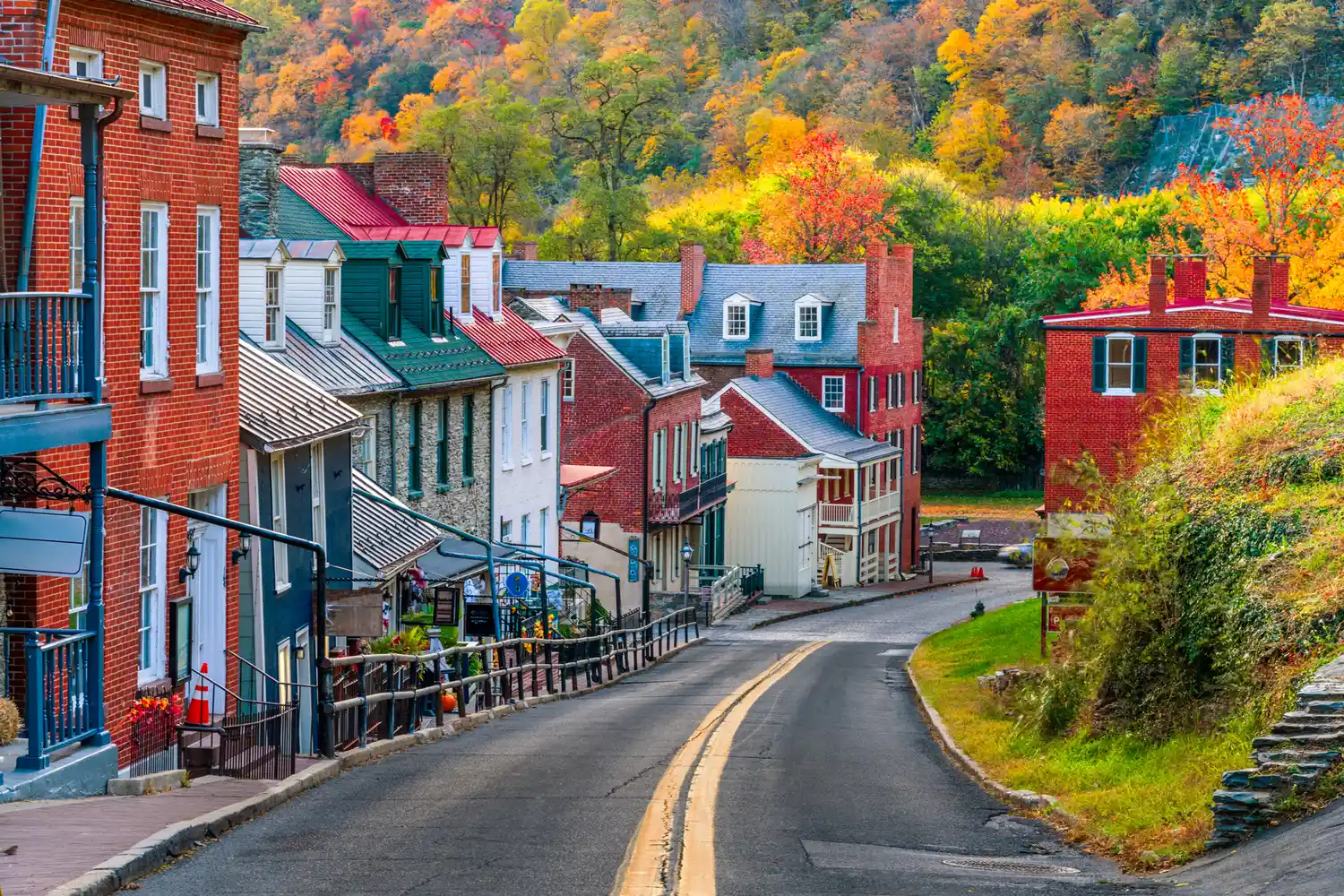 A historic street in Harpers Ferry lined with trees in peak autumn colors.