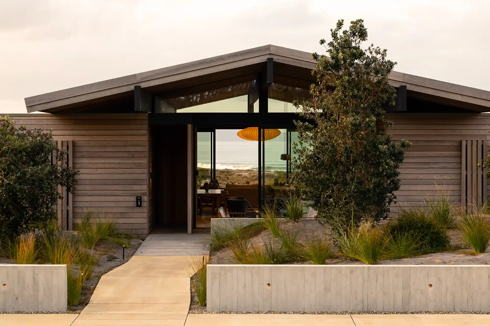 Exterior of a modern wooden villa with floor-to-ceiling glass windows at a New Zealand resort.