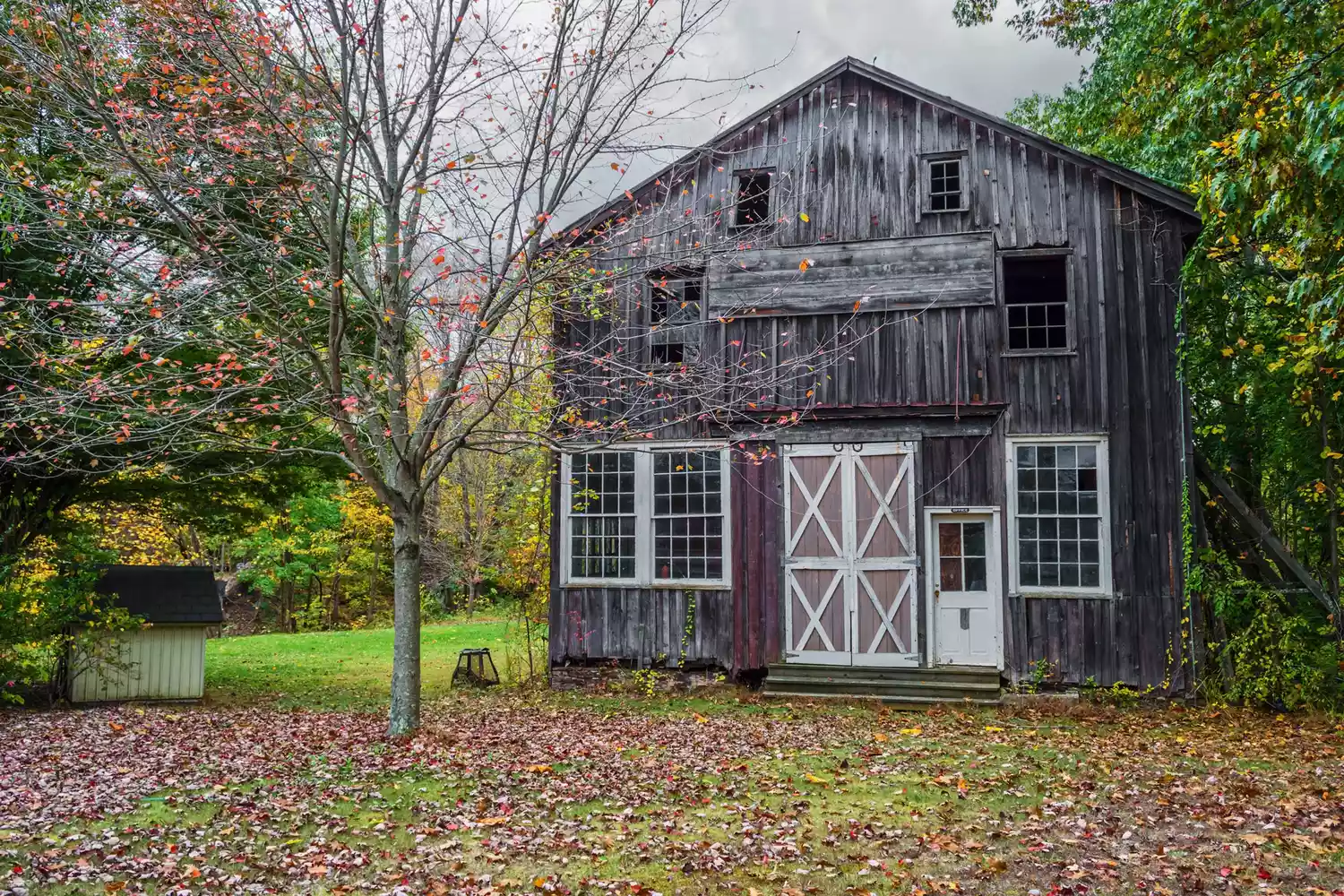 An old weathered barn surrounded by autumn trees in the rural landscape of Frenchtown, NJ.
