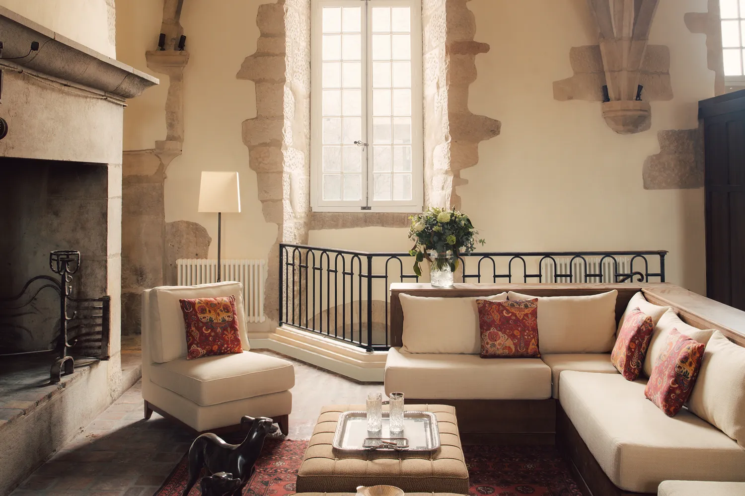 The hotel lobby featuring a large stone fireplace, contemporary armchairs, and tall windows.