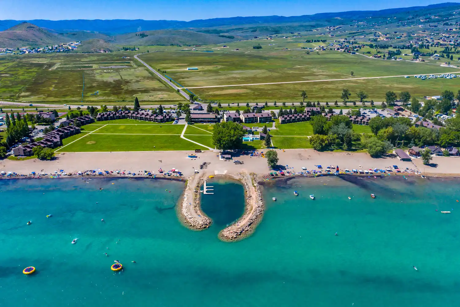 Aerial view of a dock and breakwater extending into the bright turquoise water of Bear Lake.