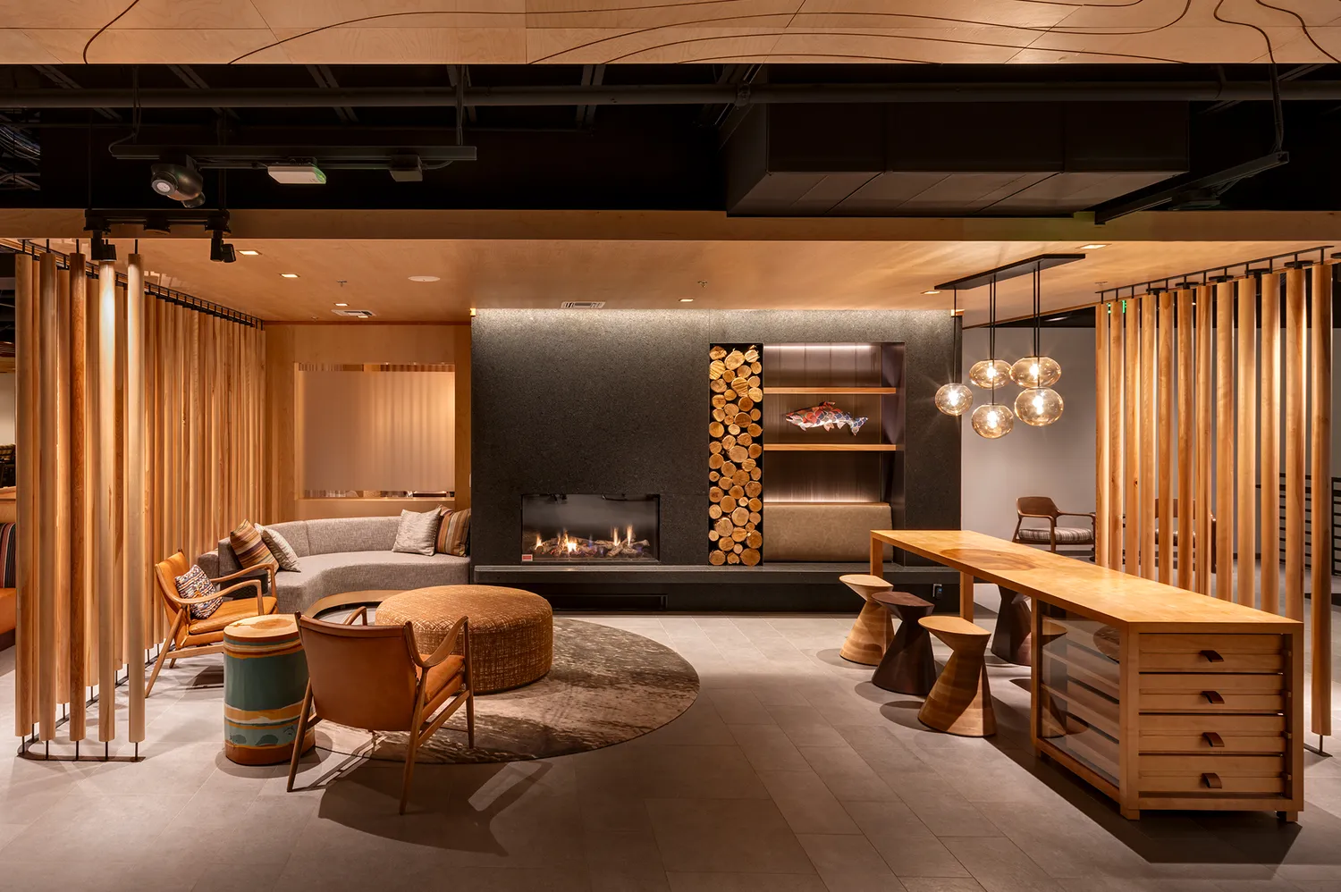 Modern hotel lobby at The Wildbirch featuring contemporary furniture and a unique firewood wall installation.