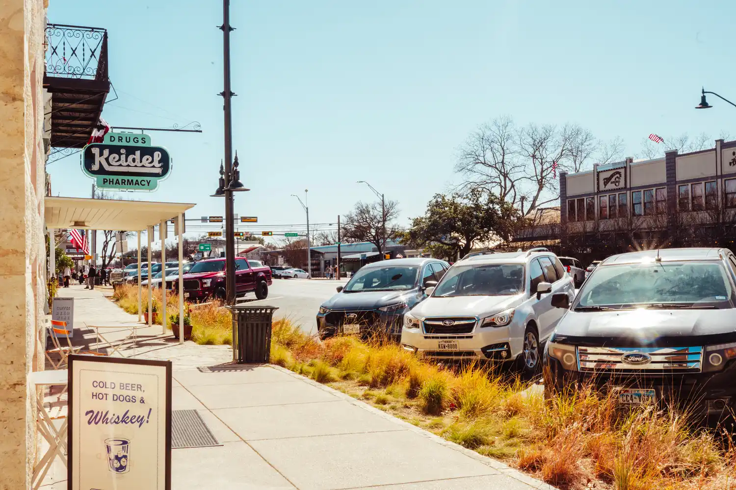 A daytime street view of Main Street in Fredericksburg with parked cars and local storefronts.