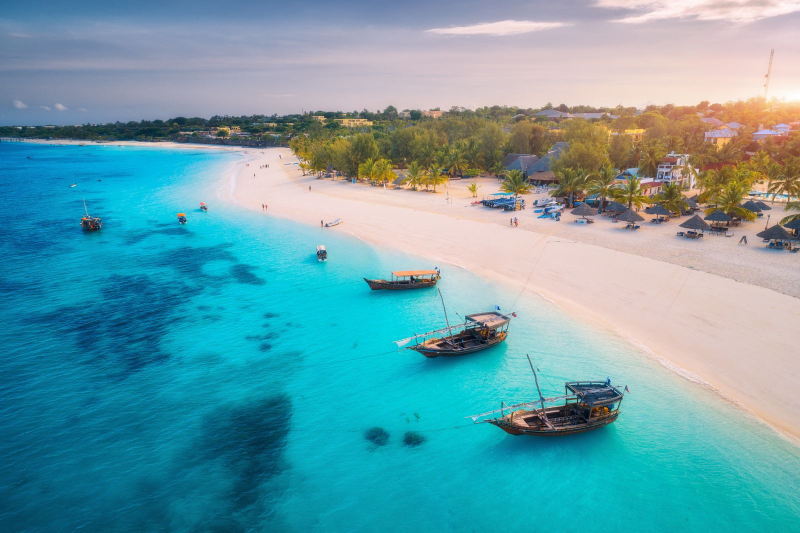 Aerial view of a coastal shoreline with clear blue water and boats.