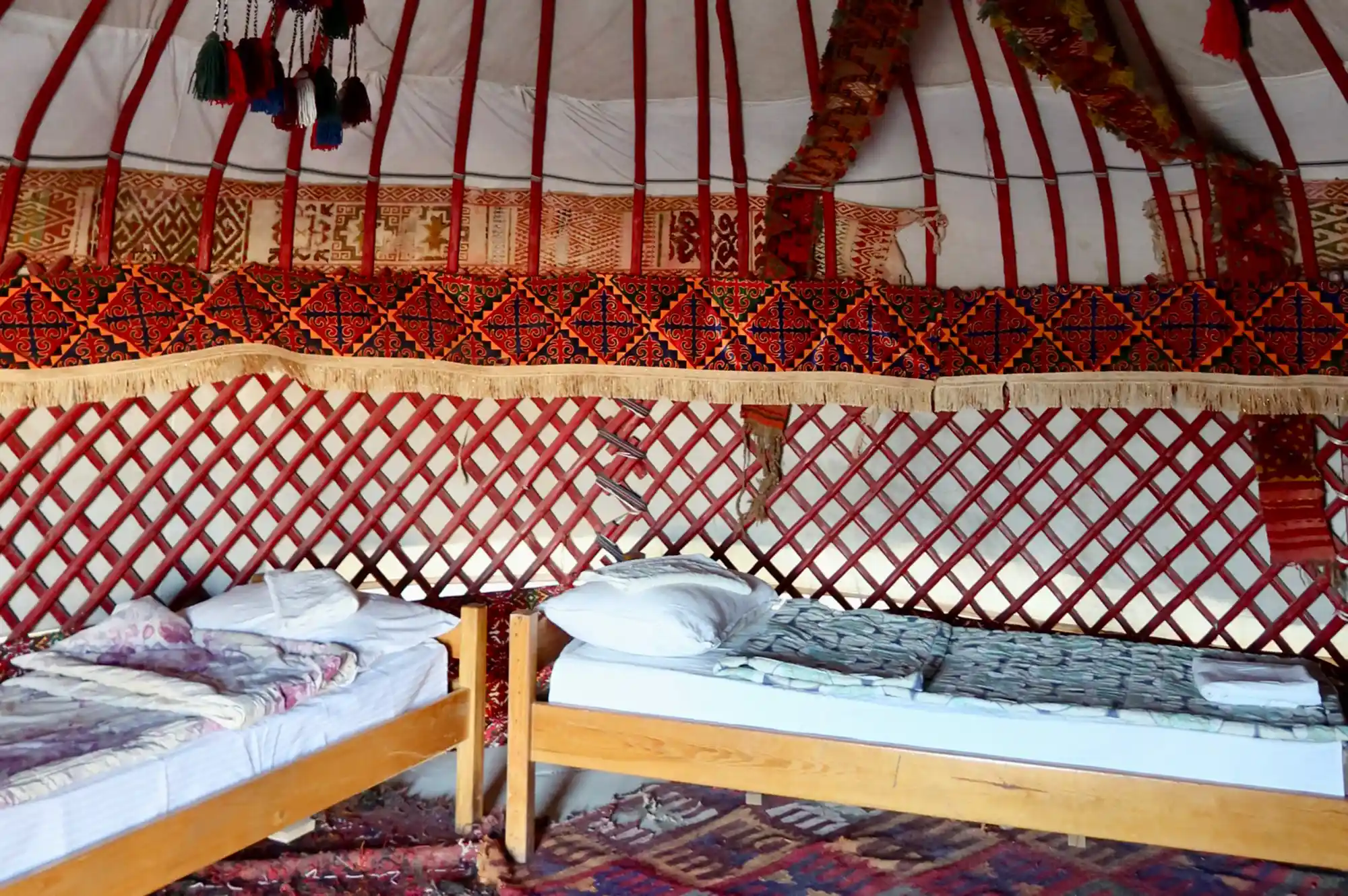 The interior of a yurt showing basic twin beds and colorful felt-lined walls.