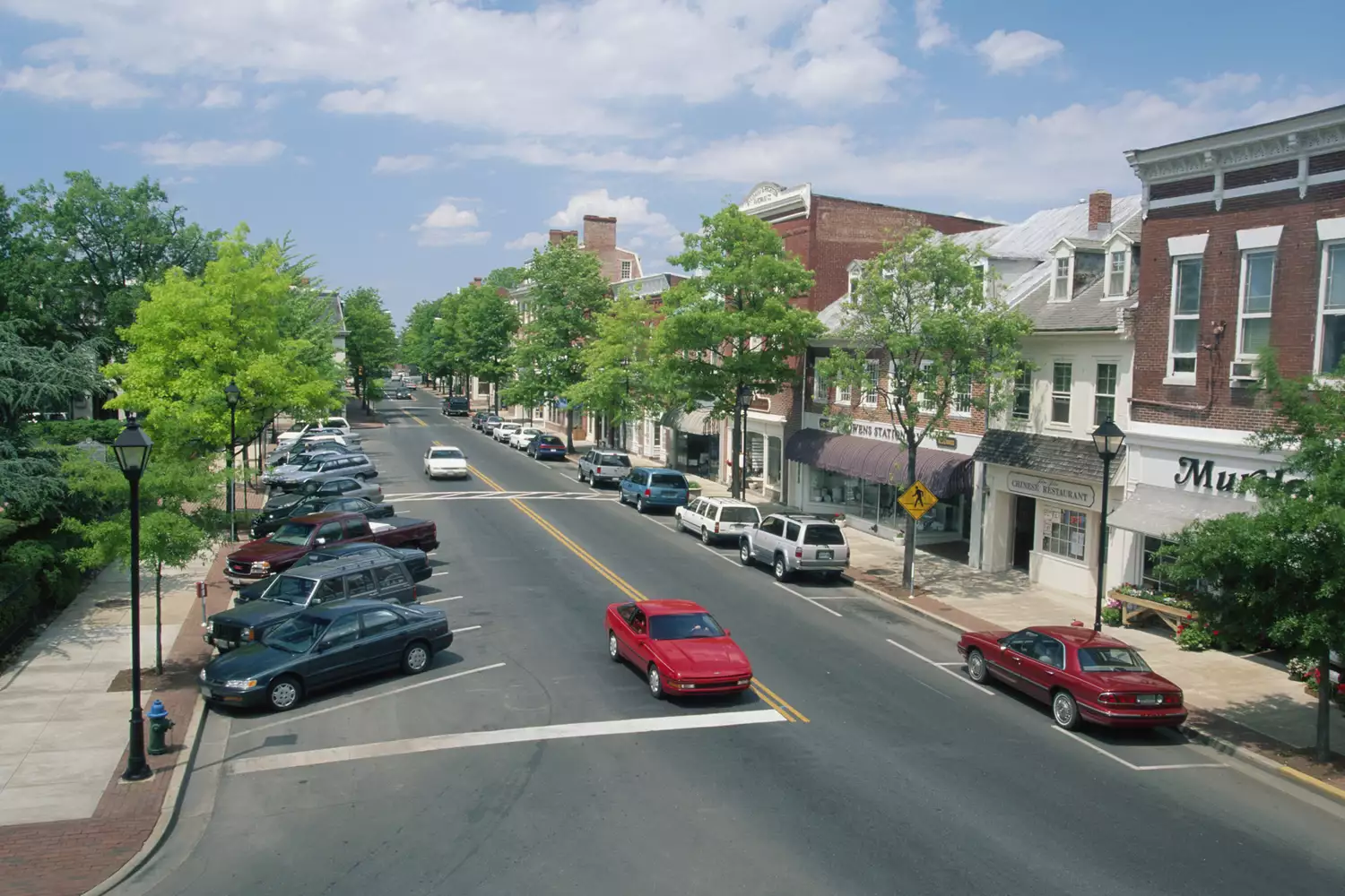 A traditional American main street with trees, cars, and well-maintained storefronts in Easton, Maryland.