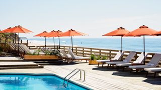 Luxury hotel swimming pool with blue water and surrounding lounge area under the sky.