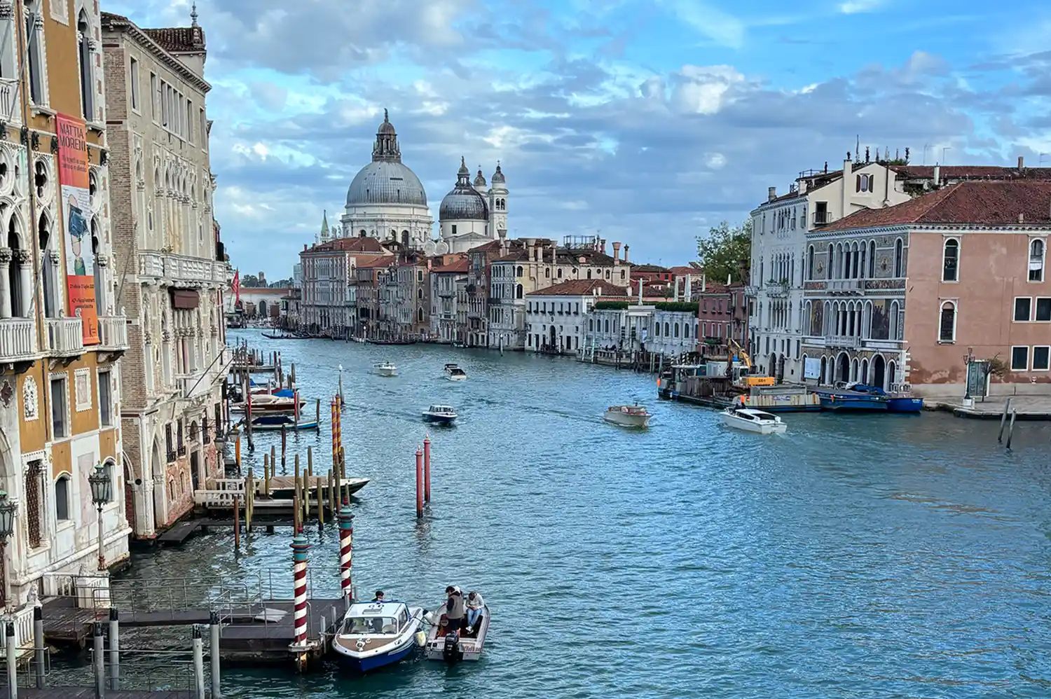A wide view of the Grand Canal in Venice featuring historic architecture and a prominent domed church.