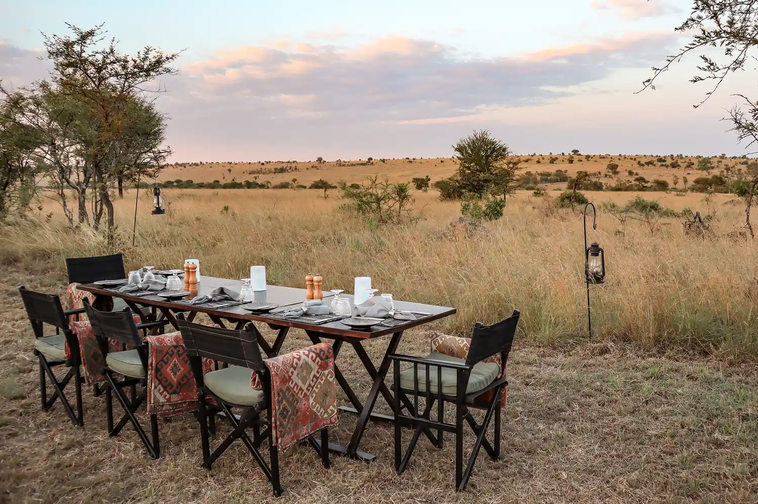 Private outdoor dining table set for a meal in the middle of the Serengeti grasslands.