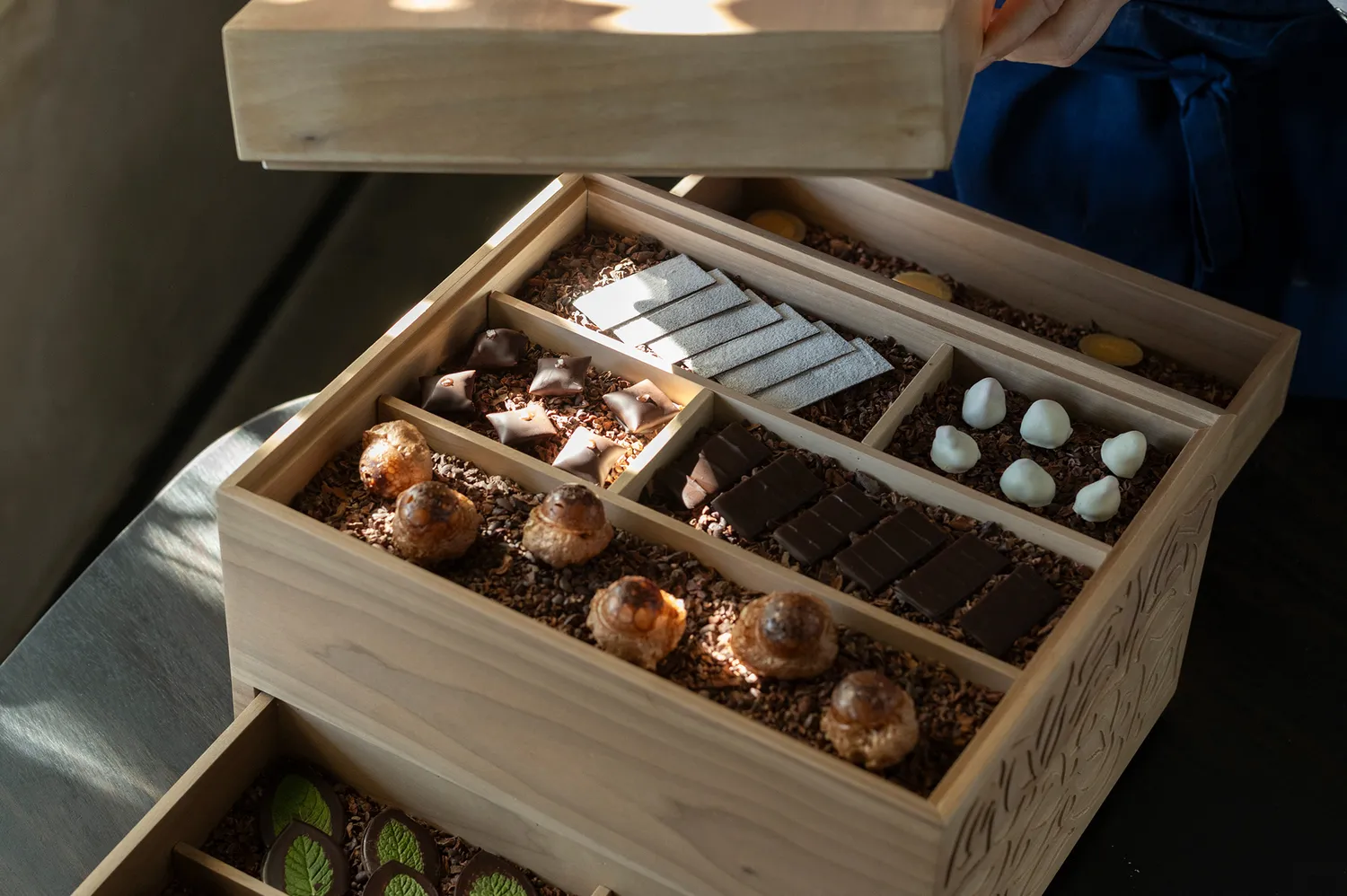 An elegant wooden box containing a variety of artisanal chocolates and petit fours.