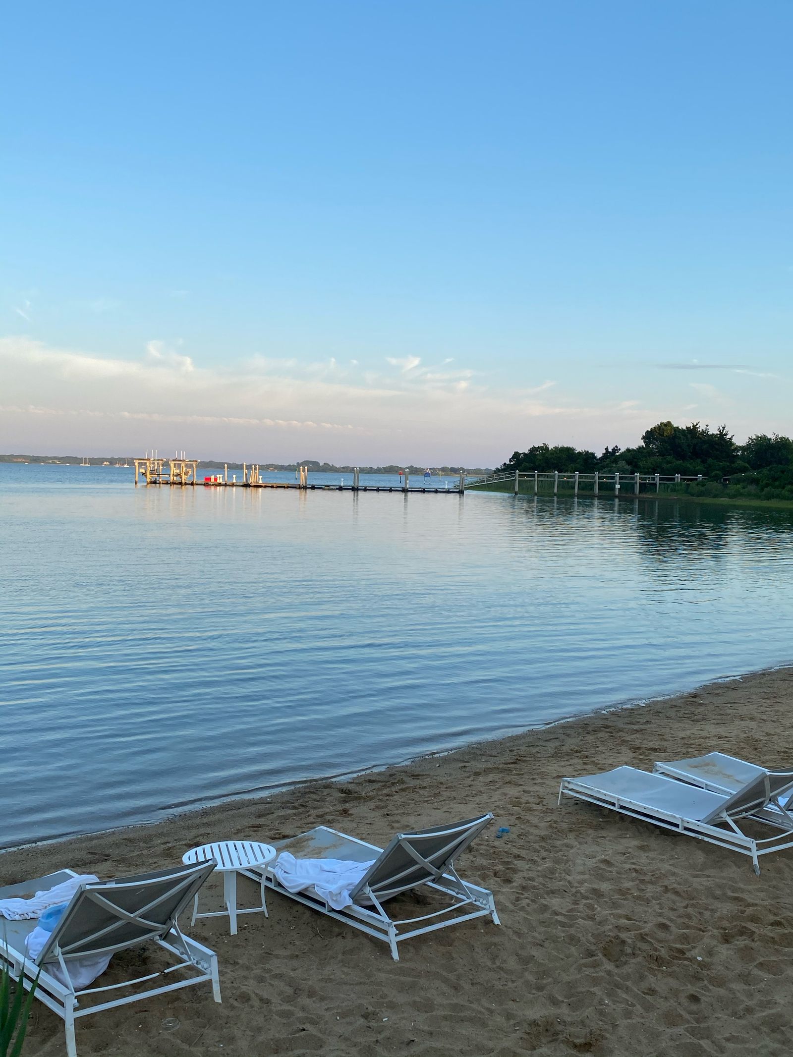 Outdoor waterfront seating with chairs facing a calm harbor at dusk.
