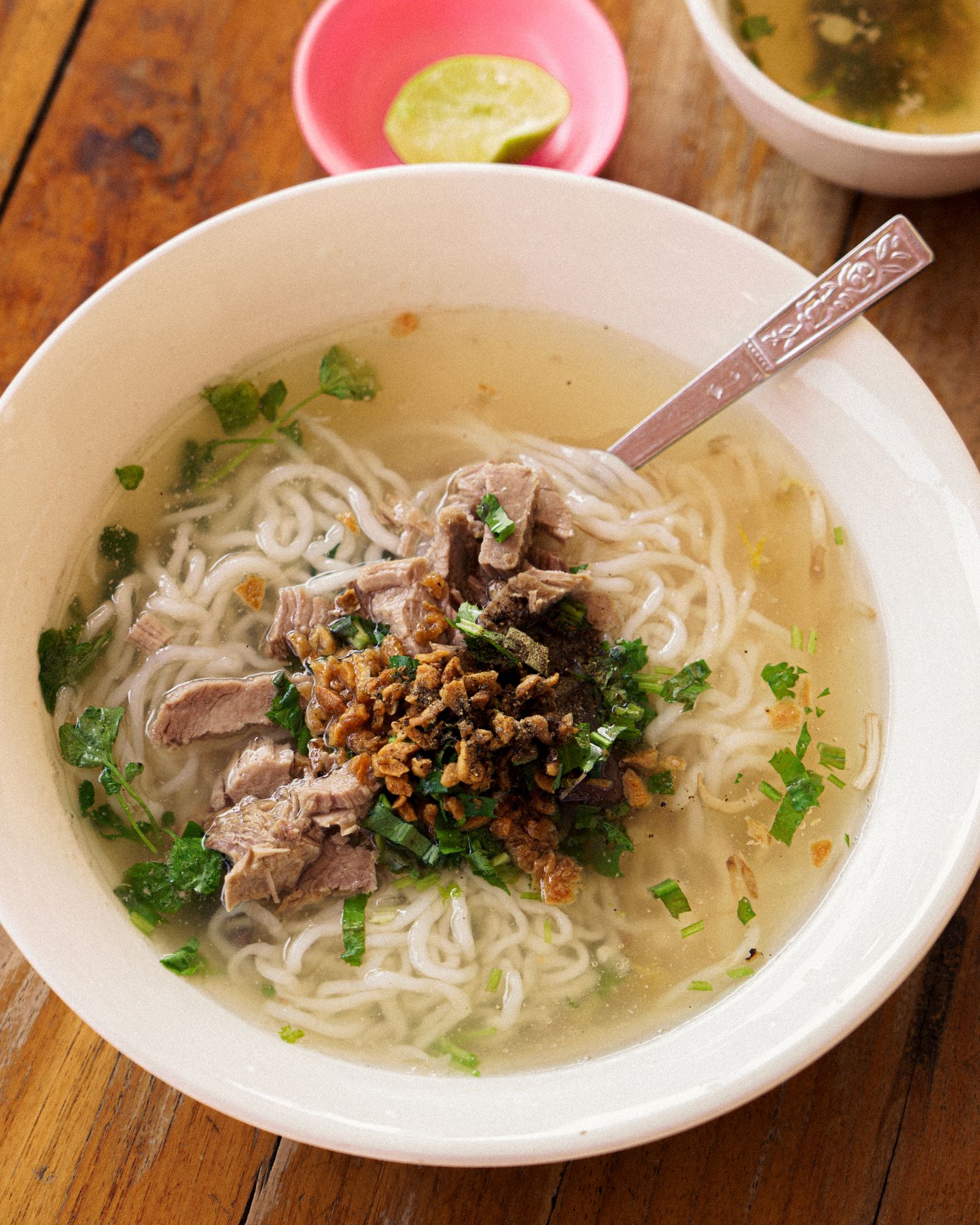 A bowl of traditional Lao noodle soup served in a local setting.