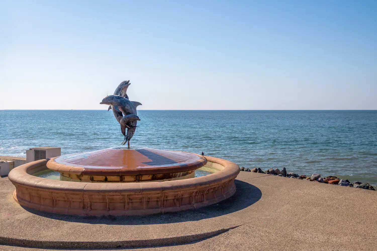 A metal dolphin sculpture on a fountain along the Puerto Vallarta seaside promenade.