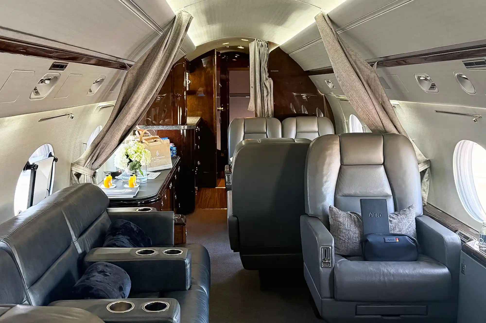 Wide-angle view of the interior of a private jet with leather seats and a clean aisle.