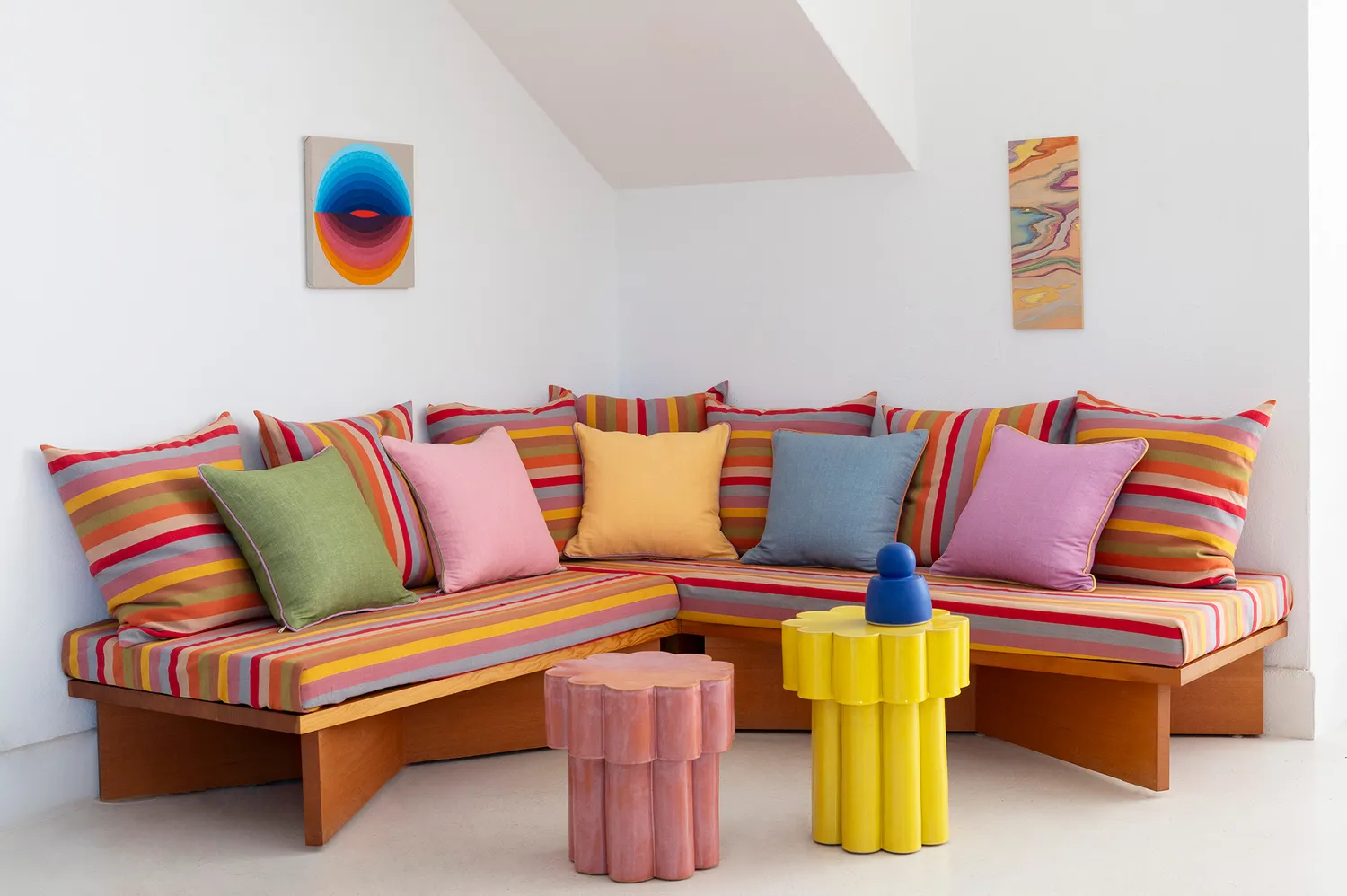 A modern sectional sofa adorned with colorful striped pillows and local artisanal decor from Garza Marfa.