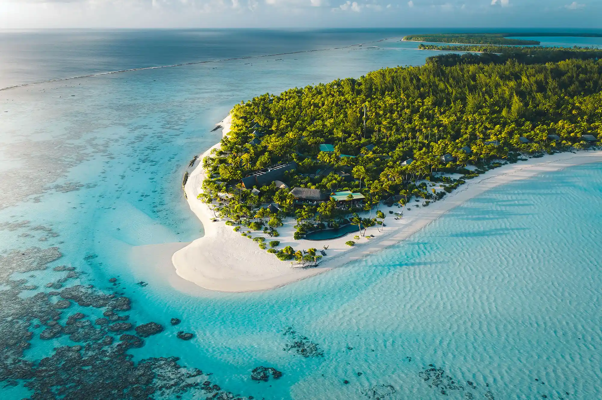 Aerial view of a lush tropical coastline with turquoise water and white sand.