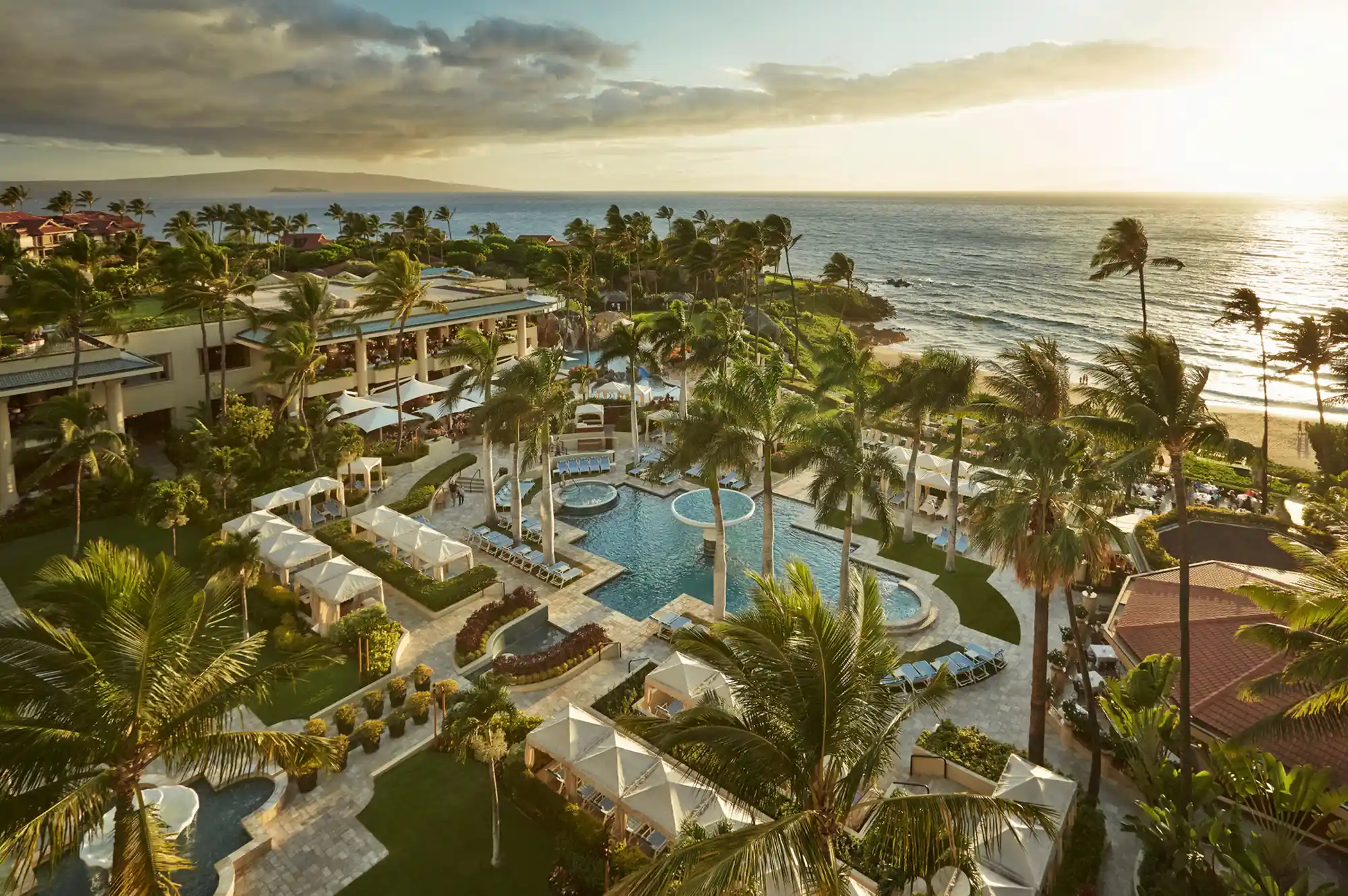 Aerial view of the Four Seasons Resort Maui at sunset with pools and palm trees.